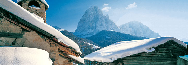 Verschneite Dächer, im Hintergrund der Langkofel